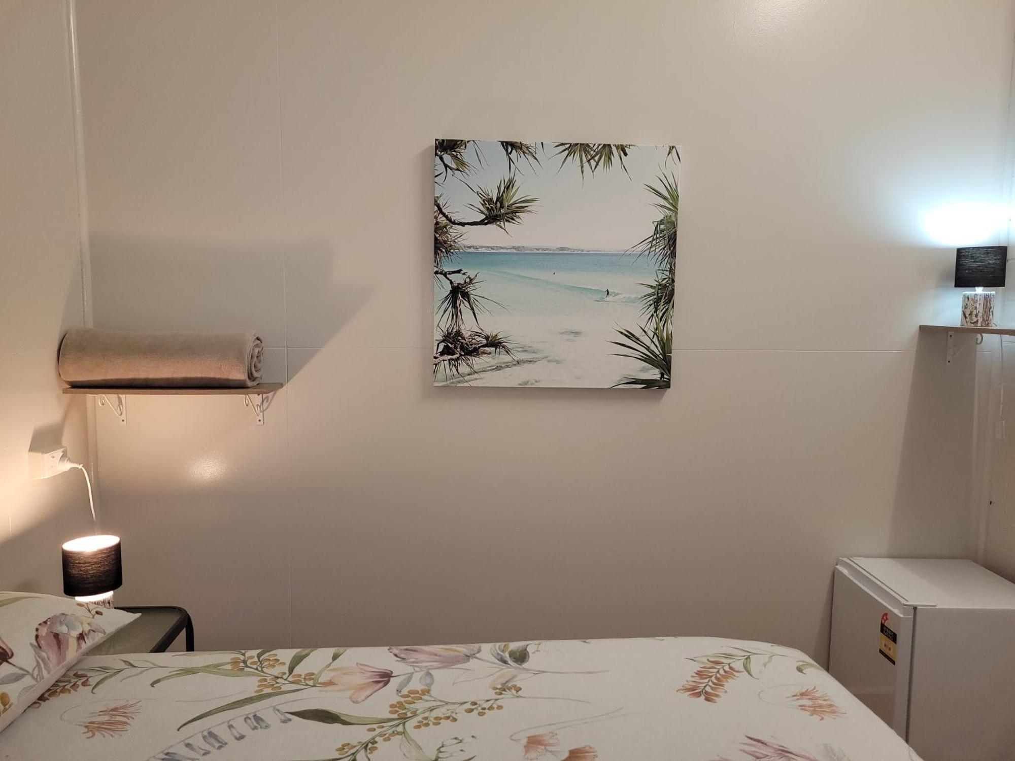 凯恩斯壁虎背包客酒店 凱恩斯 外观 照片 A photograph of a bedroom with a bed, a nightstand, a lamp, a painting, and a television